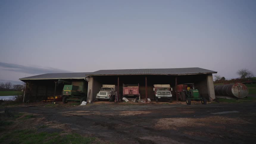 Trucks and farm machineries parked under a shelter during the day