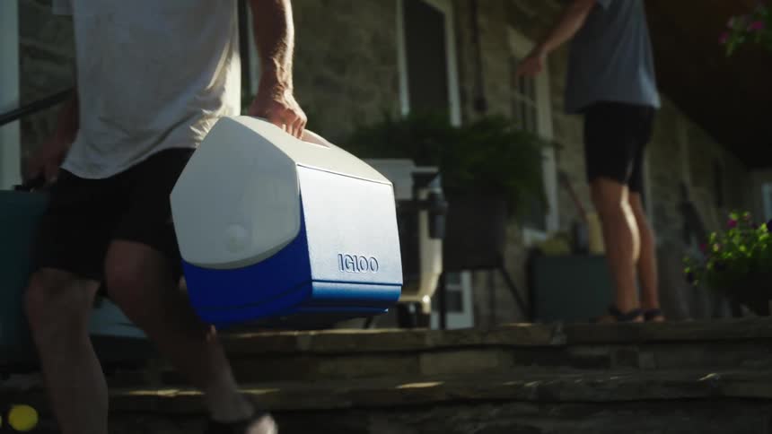 A man carries coolers from the home