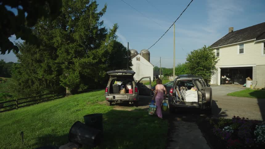 A woman walks with bags towards the car