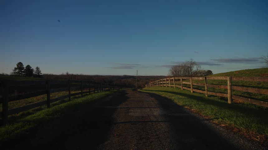 Landscape of a dirt road and surrounding fields surrounded in the morning sky with few clouds