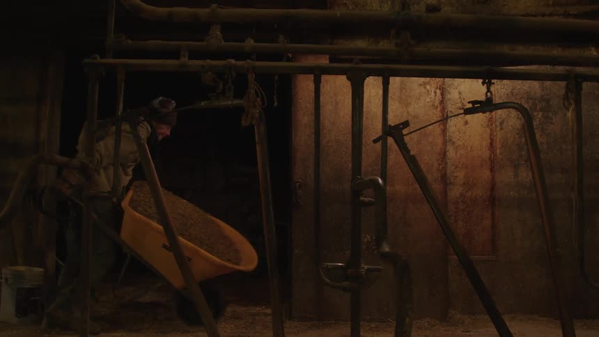 A man pushing a wheelbarrow full of hay in the barn