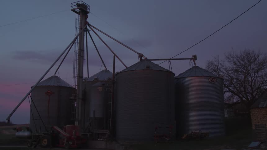 Tower and storage tanks at plant stand against a red tinted sky