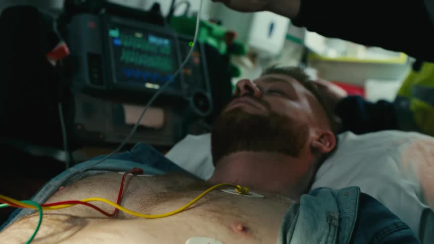 Portrait of a man lying on a stretcher with a doctor attaching monitoring equipment
