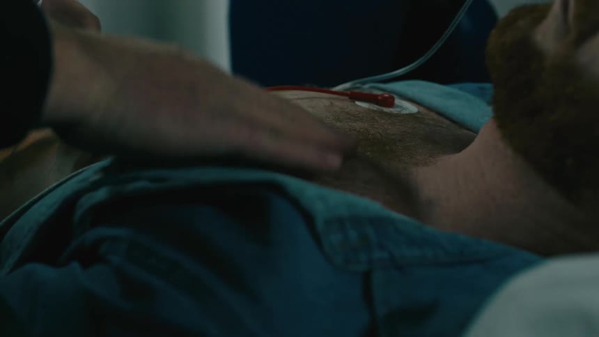 Hand of a person placing equipment on the chest of a patient who is lying on a stretcher sleeping
