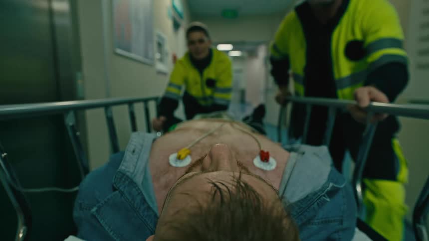A man being wheeled on a stretcher through the hospital corridor by the emergency unit