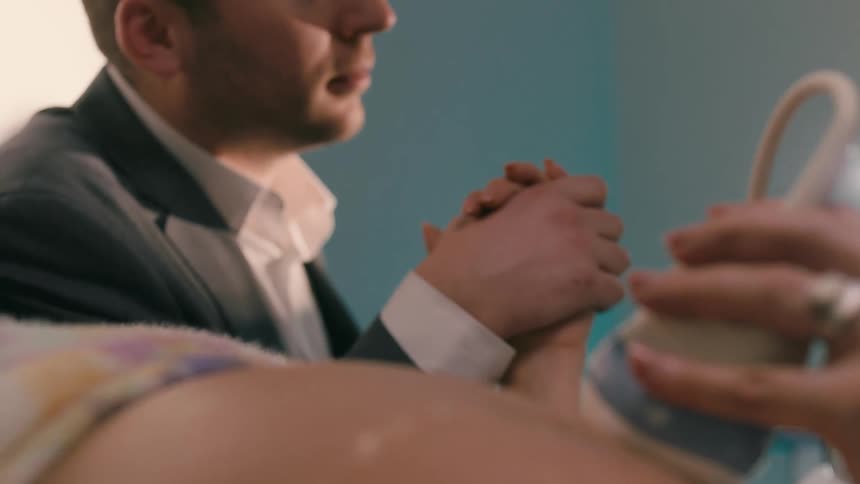 Woman undergoing an ultrasound with her husband holding her hand