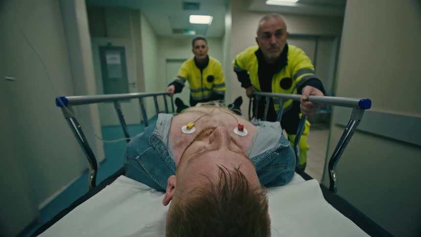 Emergency medical personnel transporting a patient on a stretcher through a hospital corridor