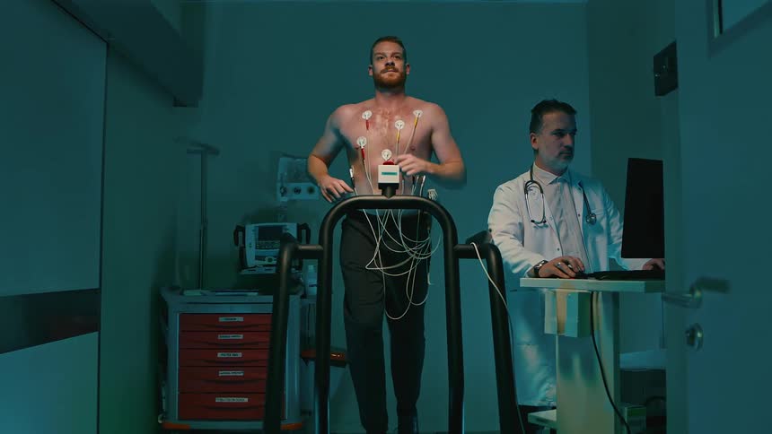 A man undergoing a treadmill test with electrodes and a doctor in a white coat
