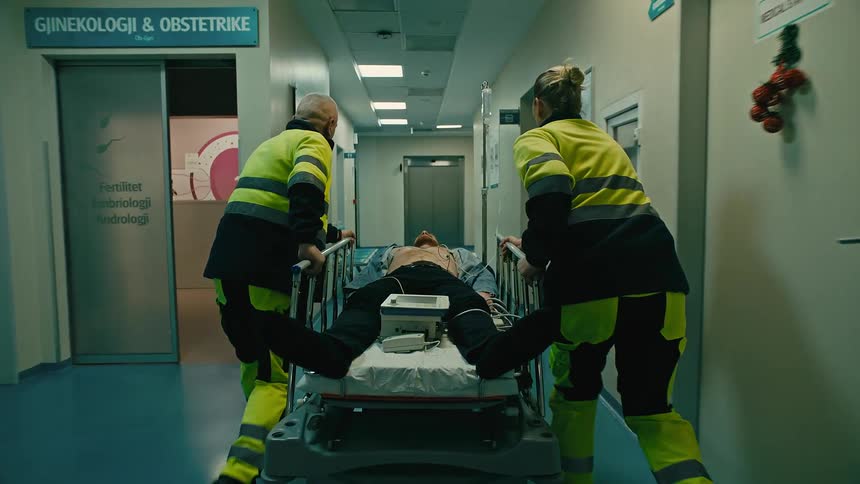 Two ambulance doctors rushing with a patient on a stretcher towards the elevator