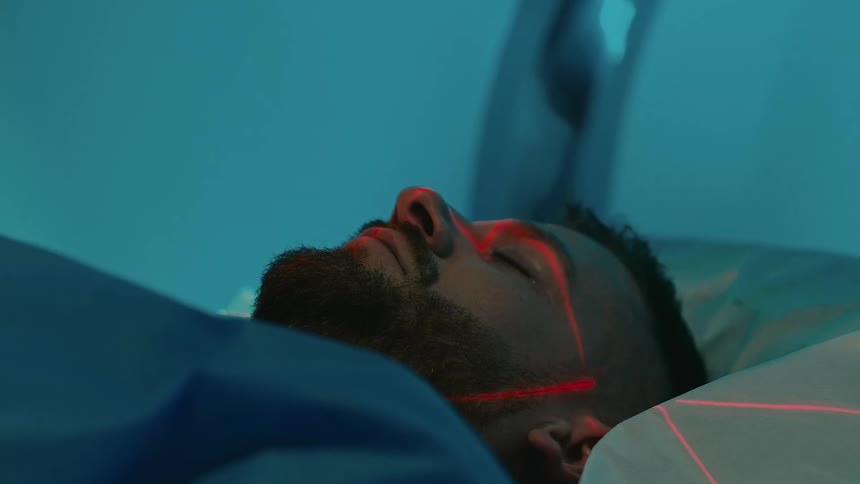 Man sleeping on a stretcher being placed inside an mri platform