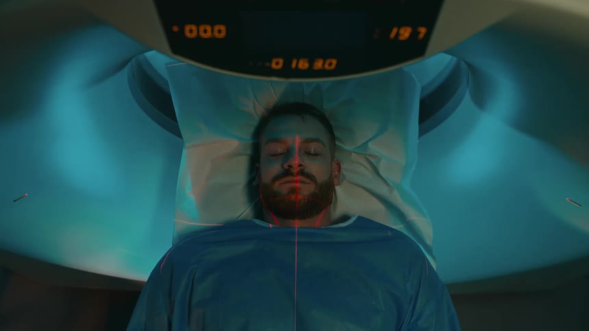 A man sleeping in a hospital bed and undergoing an mri scan