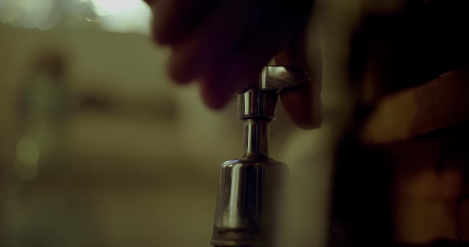 A close up of a hand turning an old fashioned tap