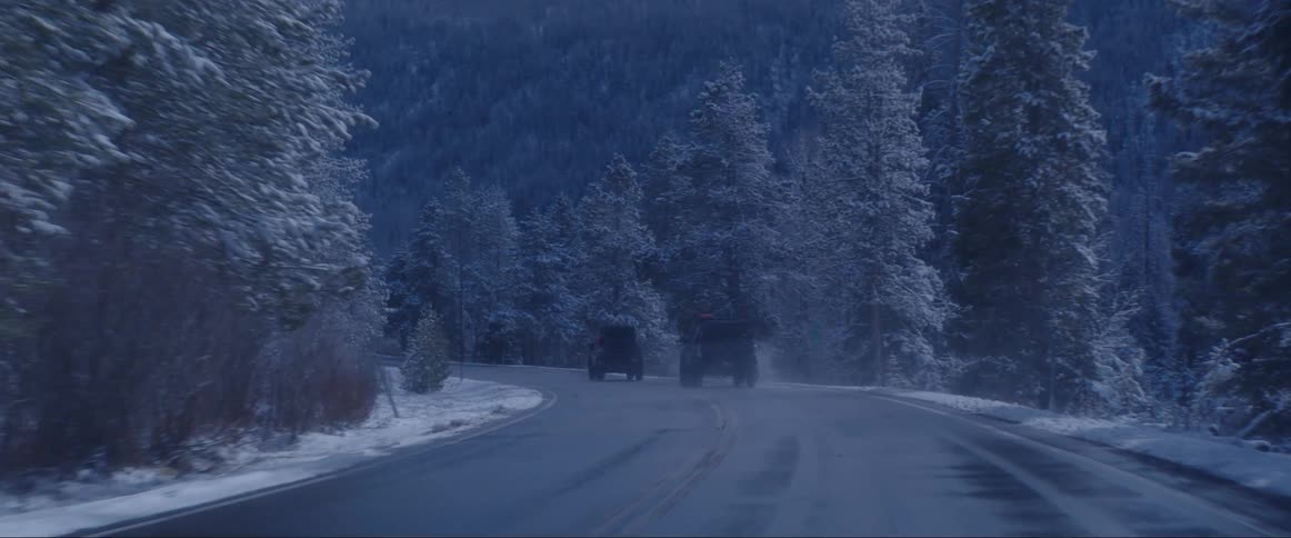 Off road vehicles travel on a snowy road in the woods