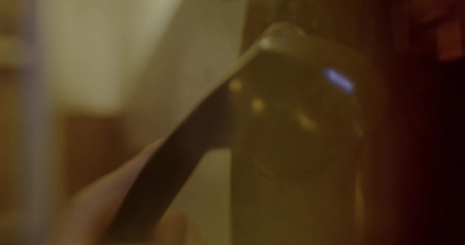 A lens flared close up of a hand dialling a wall mounted vintage telephone