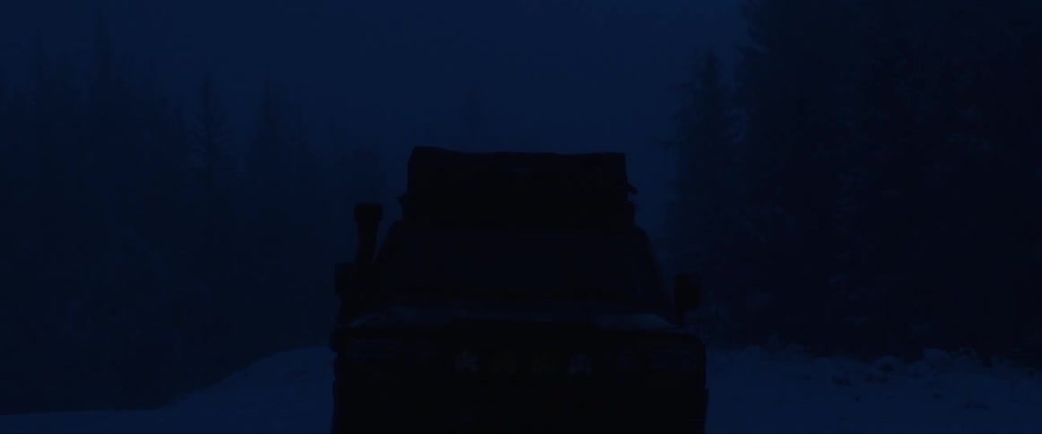 Pickup truck in the middle of the snow in the forest at night with the lights on