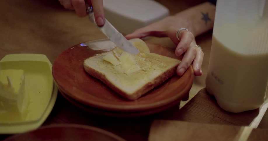 A woman butters a piece of toast