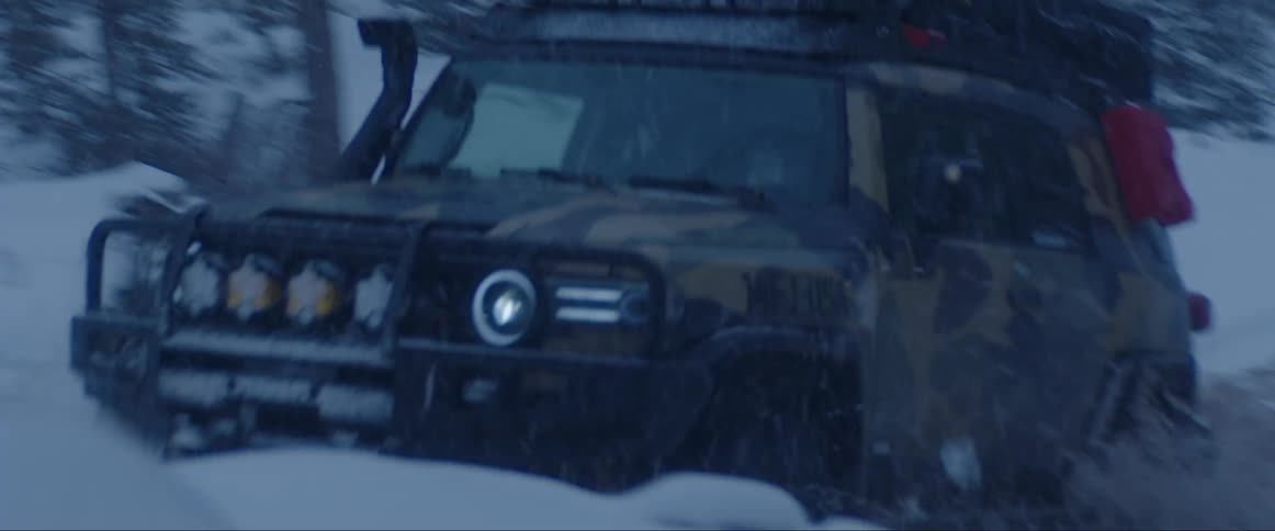 An atv driving across a snow covered forest and over a small pond