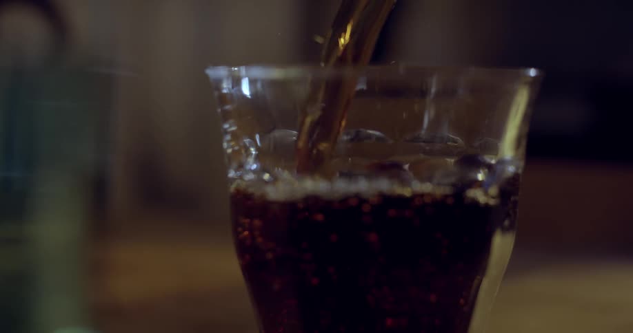 Slow motion shot of dark liquid being poured inside a glass