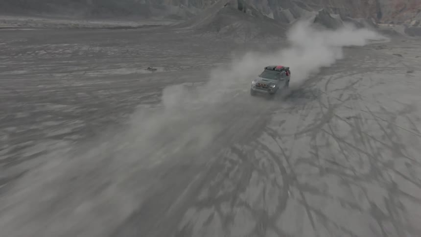 Two vehicles racing fast on a sandy road at midday