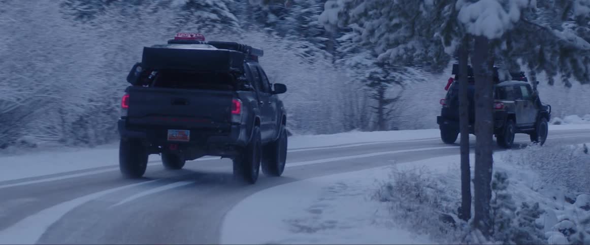 Trucks passing along a snowcovered road in the middle of a forest