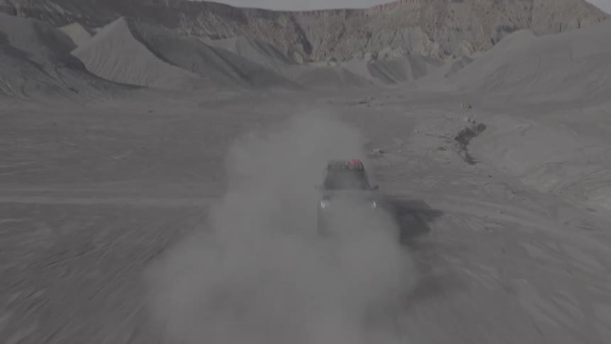Two vehicles racing in a desert during the day