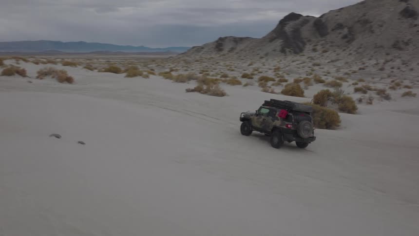 Jeep traveling through desert soil on a cloudy day