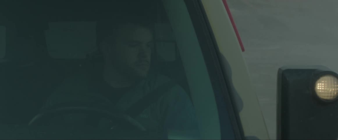 A man driving a pickup truck on a sandy road