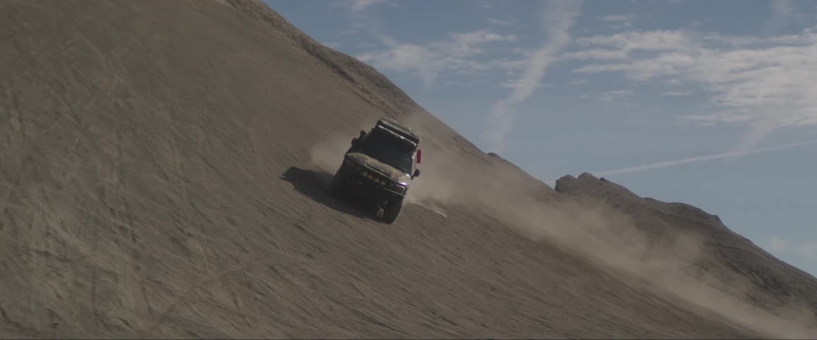 Adventure vehicle performing a maneuver along the wall of a sand dune