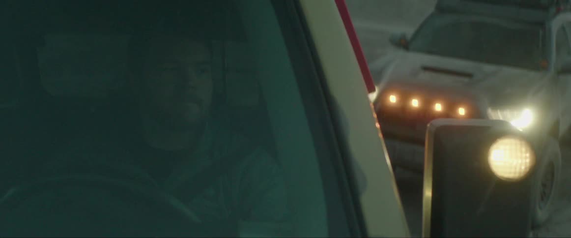 Man driving a pickup truck and climbing the ramp of a natural hill with a vehicle behind