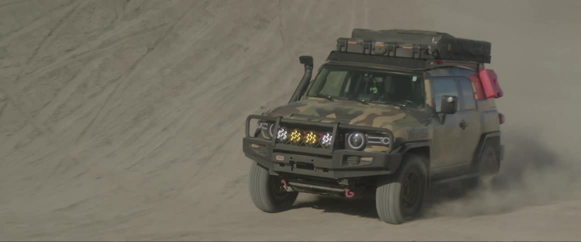 Military vehicle moving fast on the sandy road at daytime