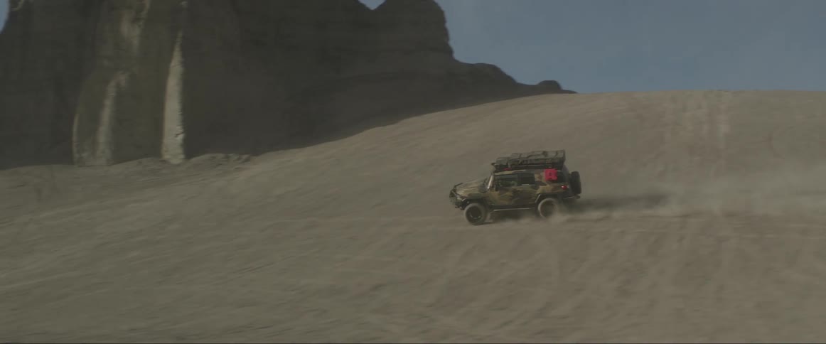 An offroad vehicle driving fast on a sandy terrain under a clear sky next to rock formations