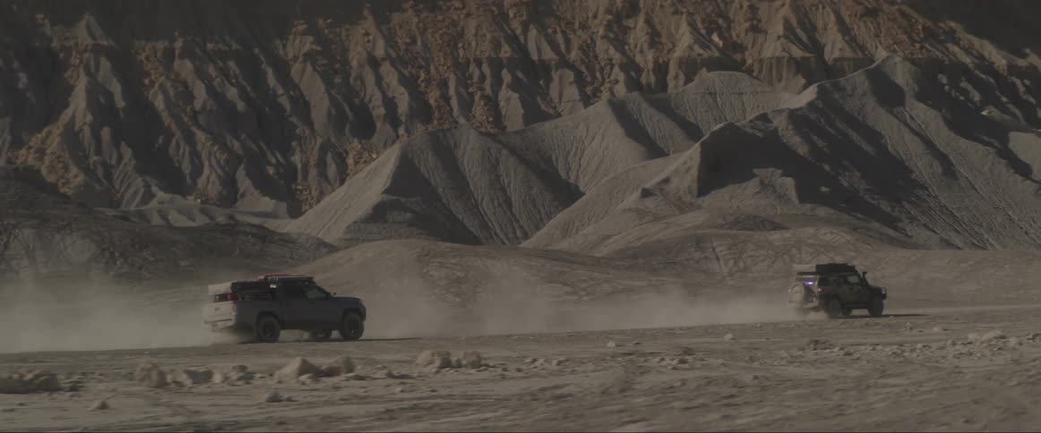 Two offroad vehicles driving fast on a rocky terrain