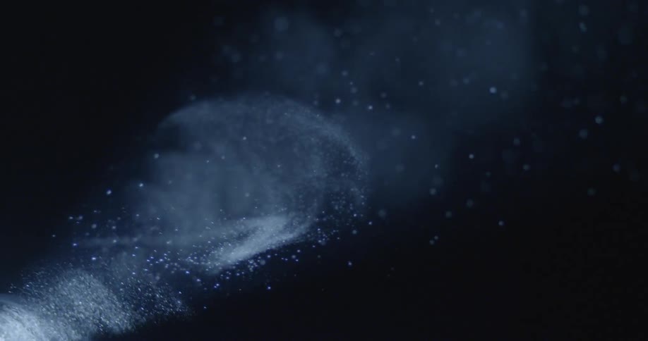 Dust swirls in a beam of light in a dark area