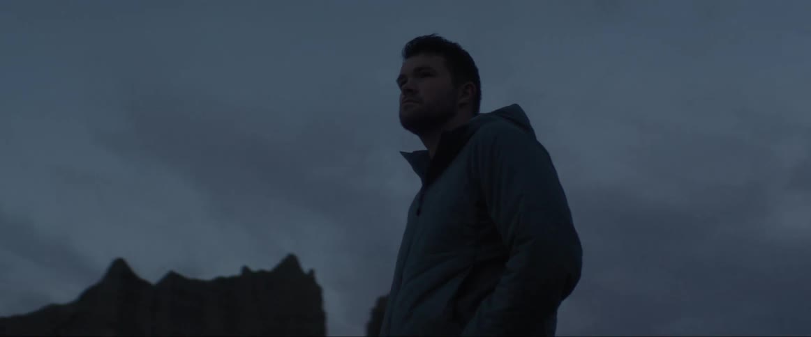 Man with pensive facial expression amidst a natural environment on a cloudy morning