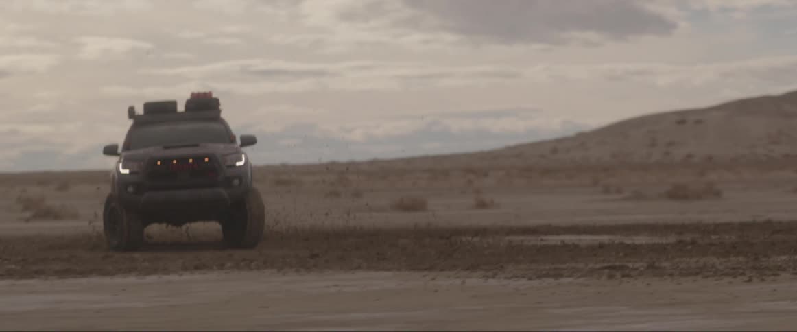 An off road vehicle spinning and kicking sand on the desert