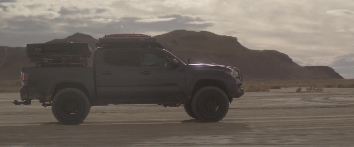 Black pickup truck traveling through desert soil