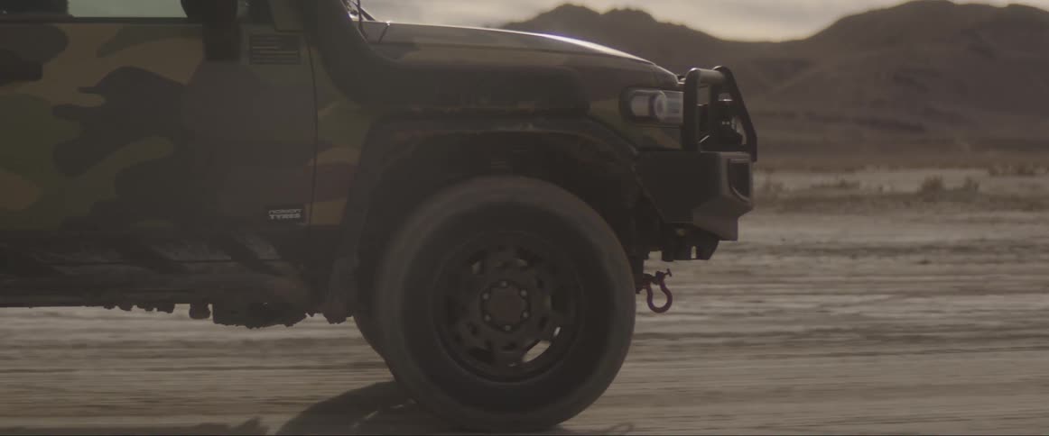 Closeup on the tire of a jeep moving across desert soil