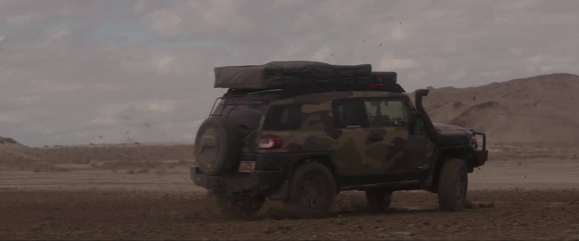 Vehicles performing stunts on a sandy road at midday
