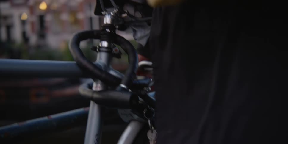 Man removing the protective strap from his bicycle that is attached to a handrail
