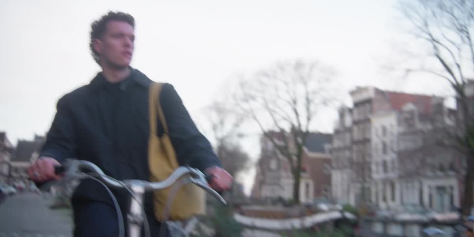 Man pedaling a bicycle along the city sidewalk