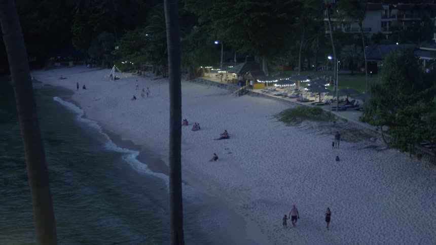 Aerial of people walking on the beach during dusk