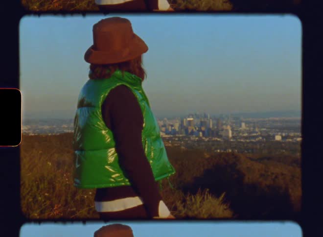 A woman in a green jacket and hat admires a city view