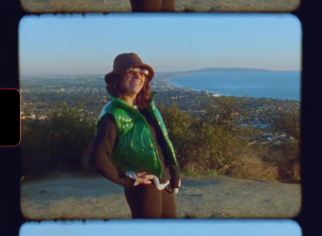 Woman happily standing on a mountain peak with a panoramic view of the city and the sea on a morning