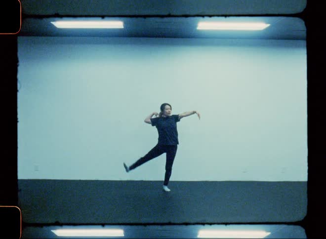 Woman in a mirrored studio dancing gesturing her arms and legs