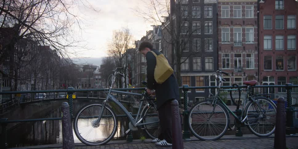 A man locking a bicycle to a handrail in the city