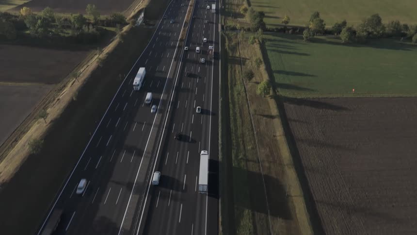 A clear day over munich on a highway with multiple vehicles surrounded by fields