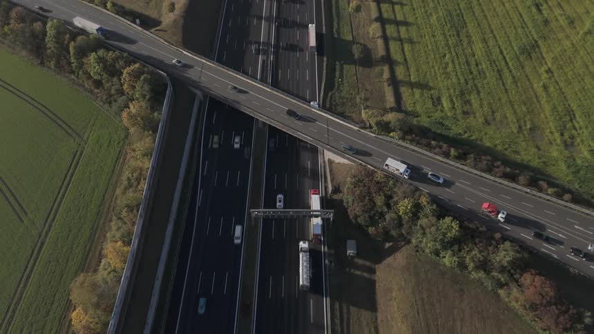Aerial panorama over munich of a highway with an overpass and vehicle traffic and agricultural fields next to it