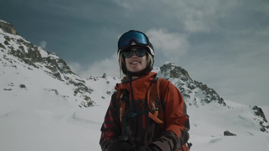 Woman skier with helmet and equipment in the middle of a mountain covered by snow