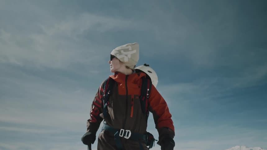 An adventurous woman climbing on ski in an icy landscape during winter