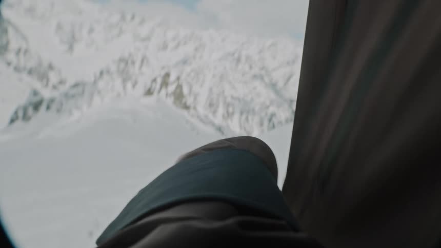 Man zipping up his jacket while standing on a snowcovered mountain peak